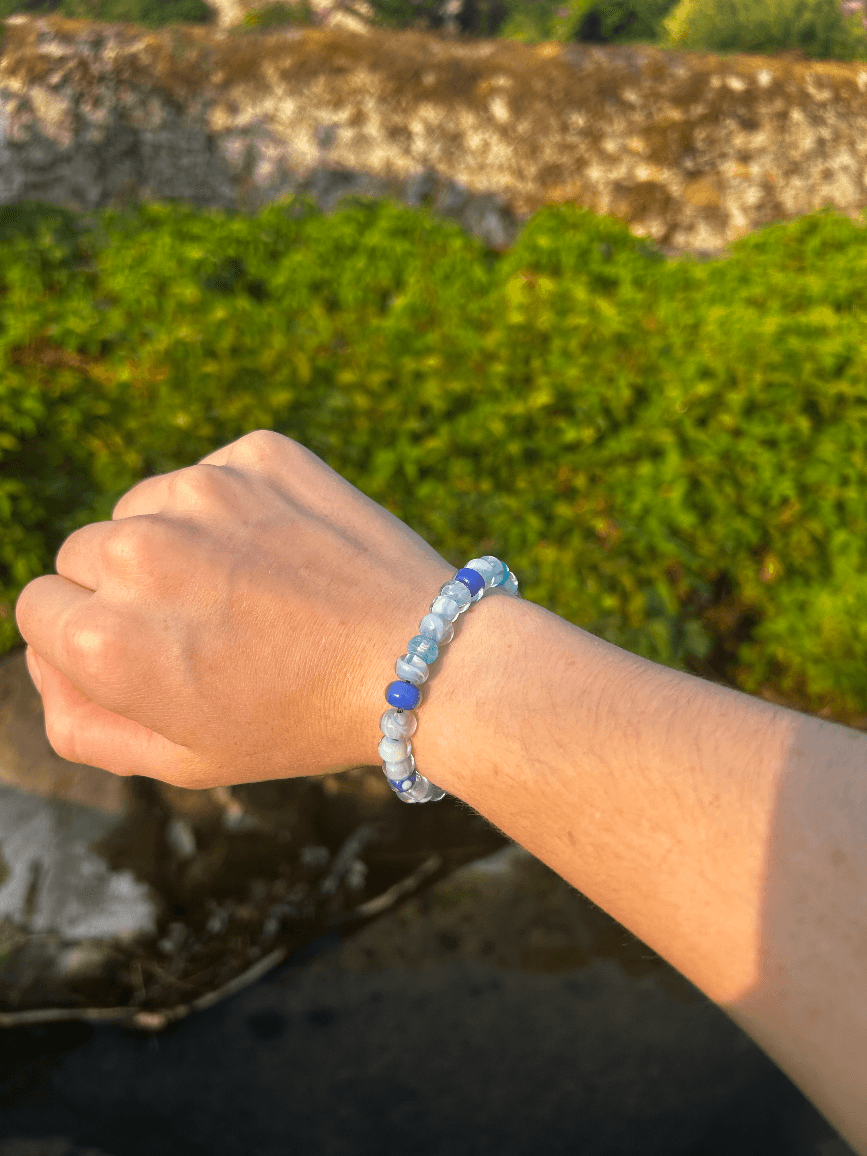 Bracelet de perles rondes aux nuances de bleu porté au poignet en extérieur
