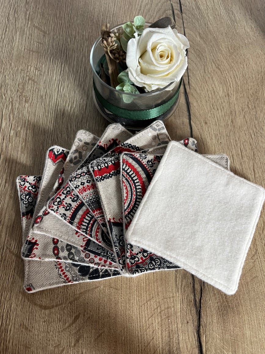 Panier souple en velours côtelé rouge et lingettes lavables disposées en éventail sur une table.