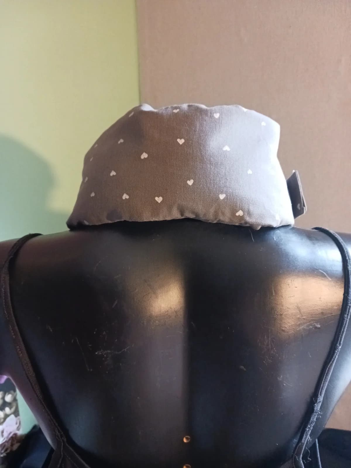 Bouillotte textile taupe à petits cœurs, forme allongée posée à plat avec attache auto-agrippante.