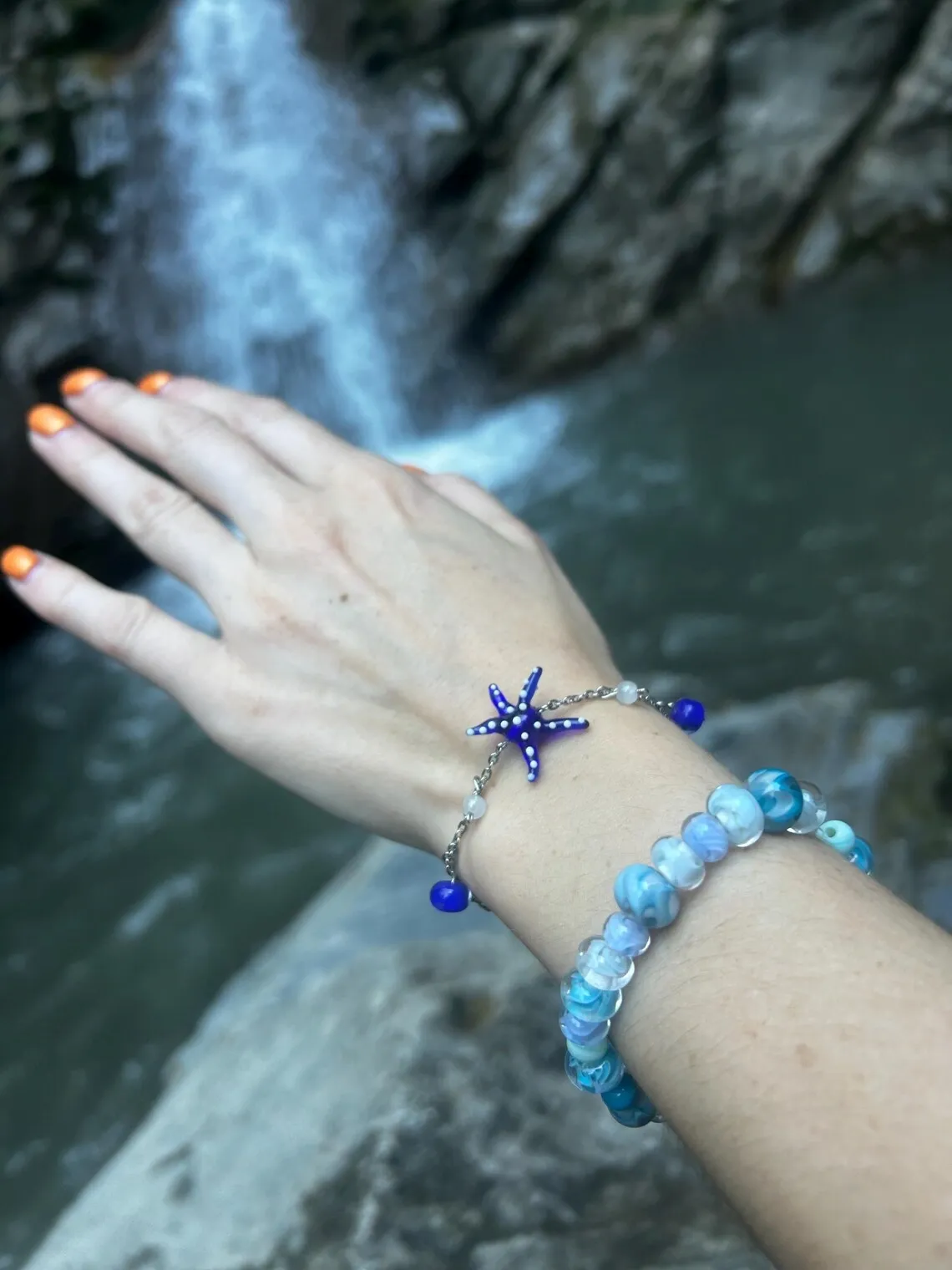 Gros plan sur le bracelet orné d'une étoile de mer bleue porté sur le bras