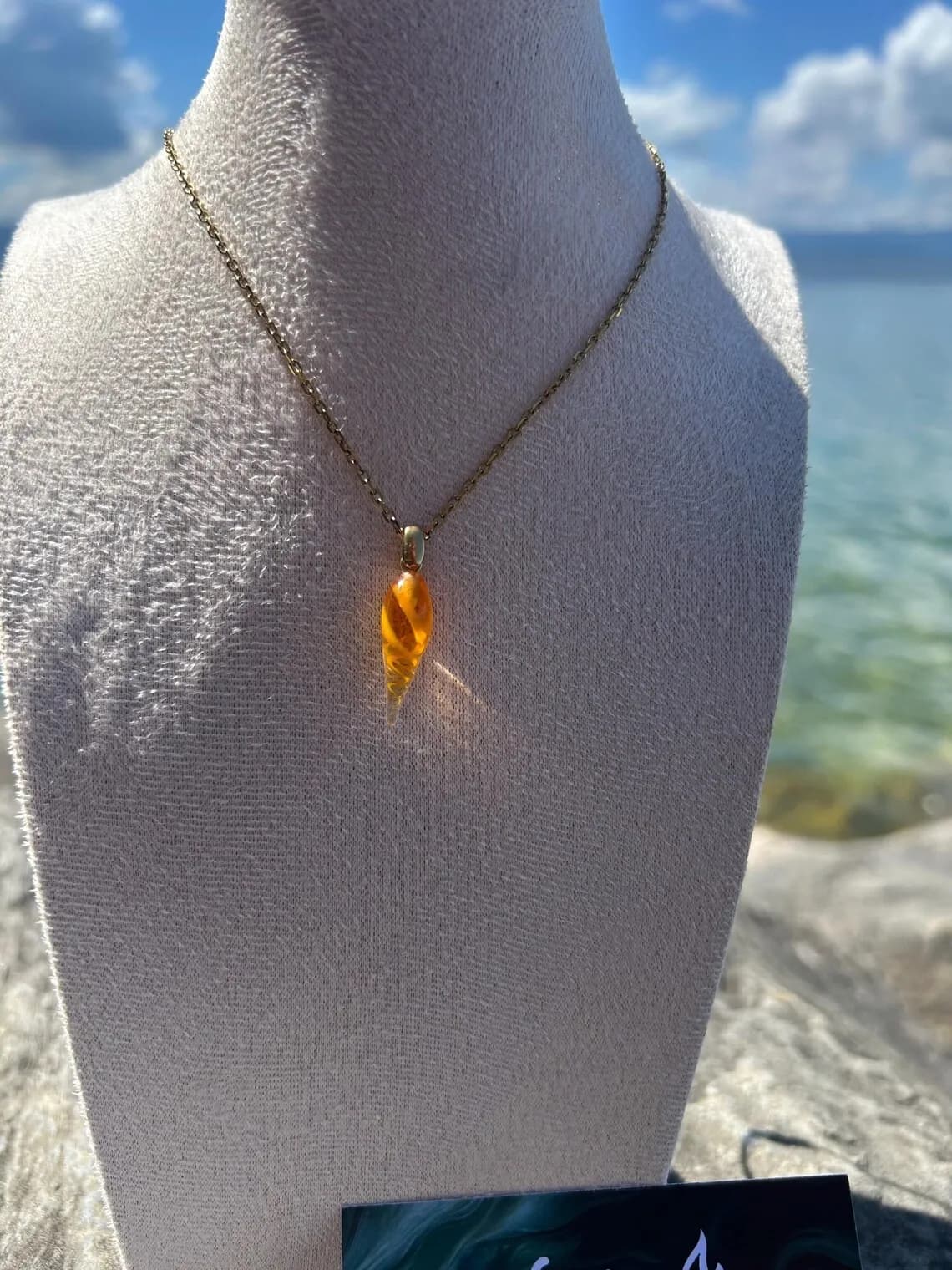 Boucle d'oreille pendante en verre orange portée au lobe de l'oreille en extérieur