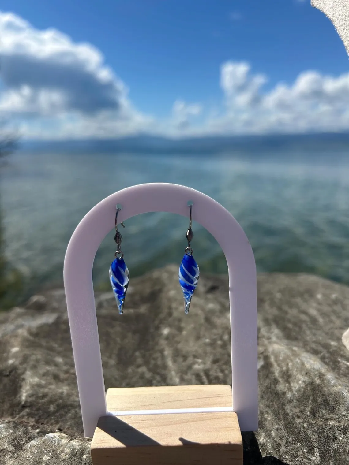 Boucles d'oreilles bleues sur support devant un buste avec pendentif assorti