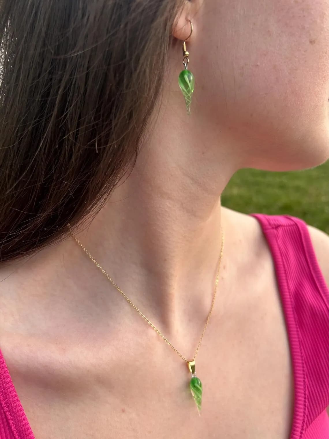 Collier à pendentif coquillage vert en verre porté au cou avec boucle d'oreille assortie.