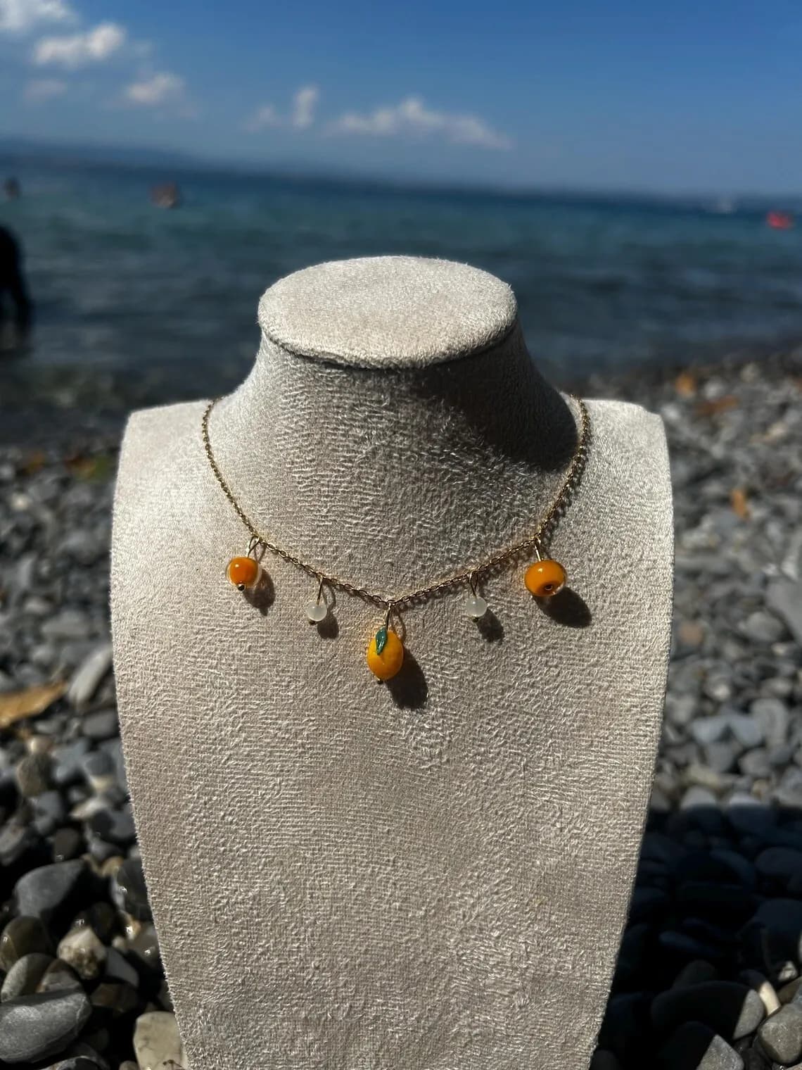 Collier fin orné de petits citrons jaunes porté au cou avec boucle d'oreille assortie.