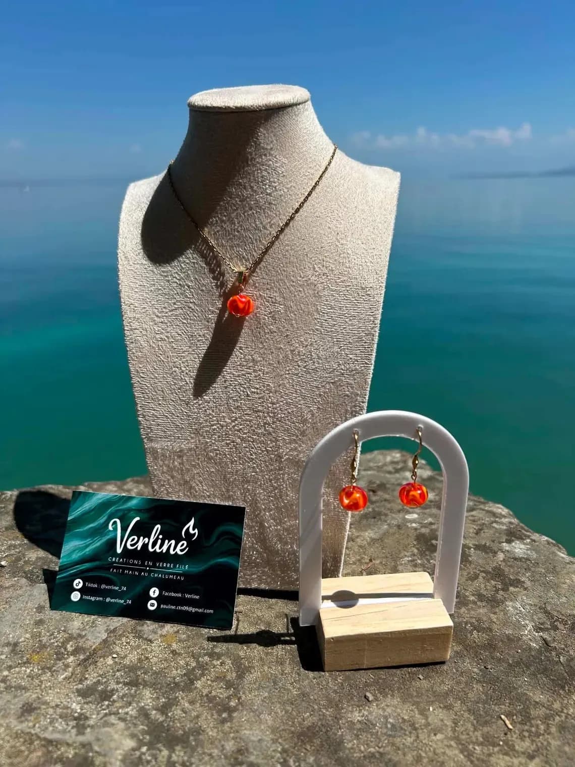Collier et boucles d'oreilles assortis avec perles en verre orange sur présentoirs en extérieur