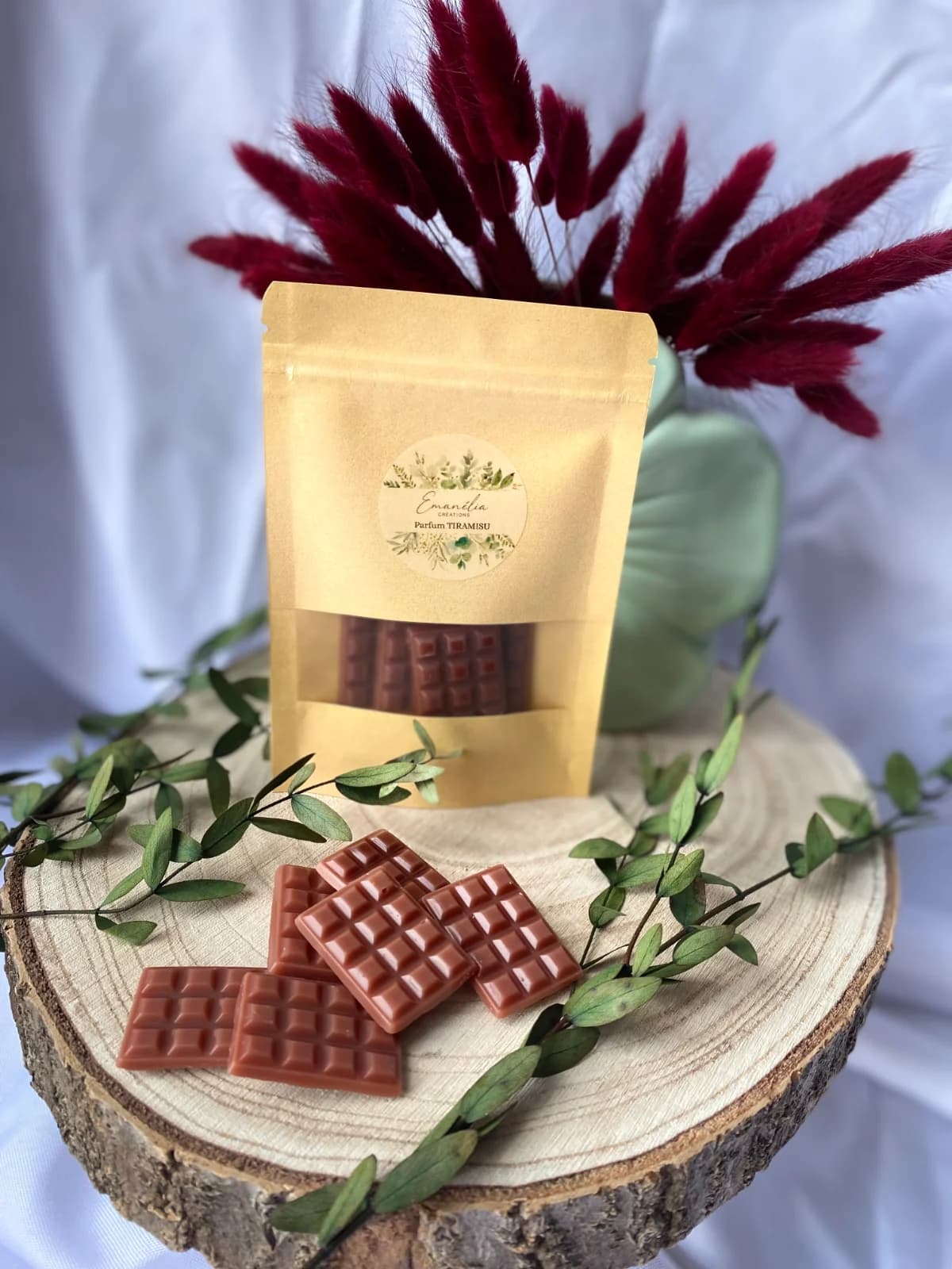 Fondants parfumés marron en forme de mini tablettes et sachet kraft posés sur un socle en bois.